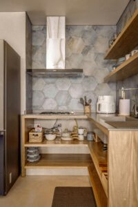 A cozy Scandinavian style kitchen with wooden shelves and hexagonal tiles.