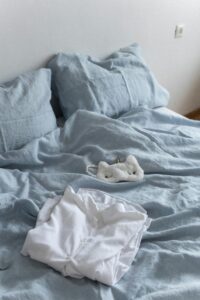 A cozy bedroom with light blue linen bedding and white pajamas, perfect for a relaxing atmosphere.