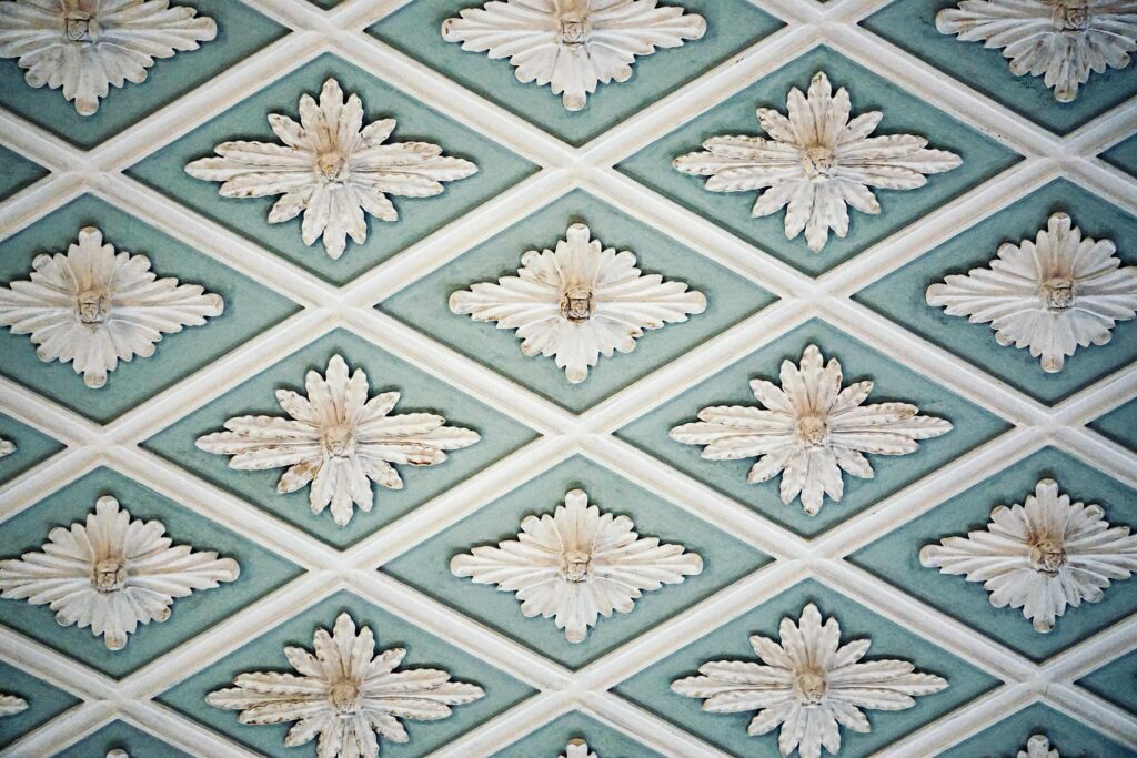 Intricate floral pattern on a decorative ceiling with soft blue and white hues.